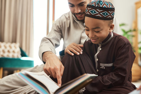 A reader lives a thousand lives before he dies. a young muslim man and his son reading in the lounge at home.の写真素材