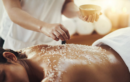 Woman, hands and salt in massage at spa for skincare, exfoliation or body treatment at resort. Hand of masseuse applying salts to back skin for relaxation, therapy or zen in healthy wellness at salonの写真素材