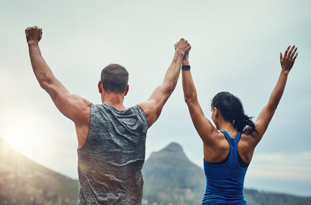 Couple, celebration and arms up in nature for training, workout or exercise to run a marathon, competition or tournament. People, winning and happy for freedom, sports goal or achievementの写真素材