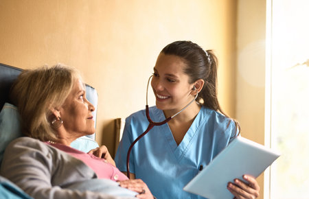 According to the records, youre doing way better. a nurse examining a senior patient with a stethoscope.の写真素材