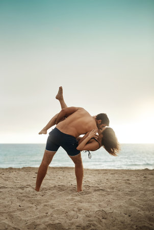 Enjoying a romantic beach day. a young man holding his girlfriend on the beach.の写真素材