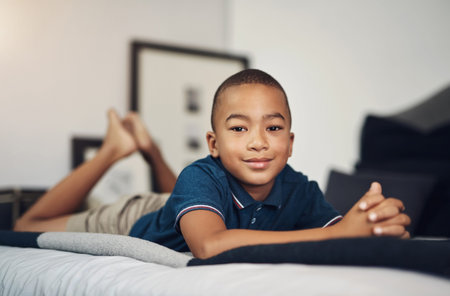 Mom says Im good at keeping my room tidy. an adorable young boy lying on his bed.