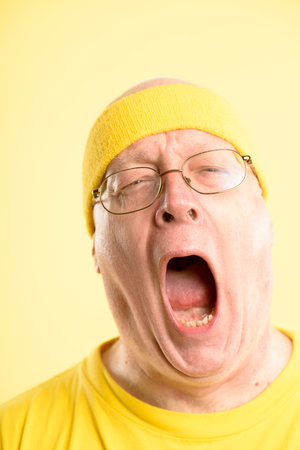 I really need a nap. a mature man standing alone in the studio and yawning.の写真素材