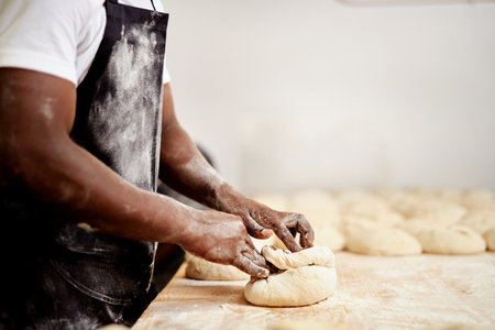 After rolling these up Ill let then sit for a few minutes. a male baker busy shaping dough at work.の写真素材