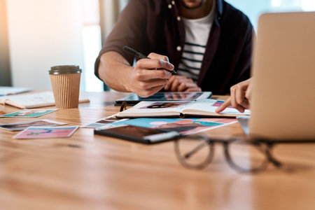 Make notes so we dont forget anything. two unrecognizable businesspeople sitting together and having a meeting over polaroids in the office.の写真素材