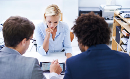Making educated decisions. a serious businesswoman looking at information presented to her by...