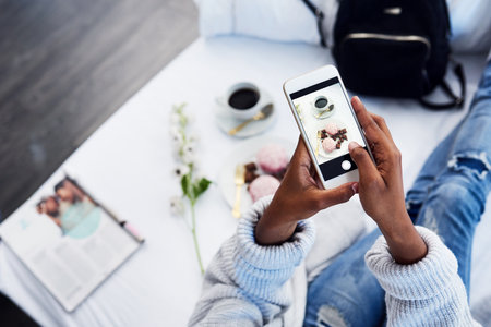 Black woman hands, social media and photo for food blog with cake on hotel bed. Top, female person and screen of a freelance blogger with dessert, technology and vlog with entrepreneur in roomの写真素材