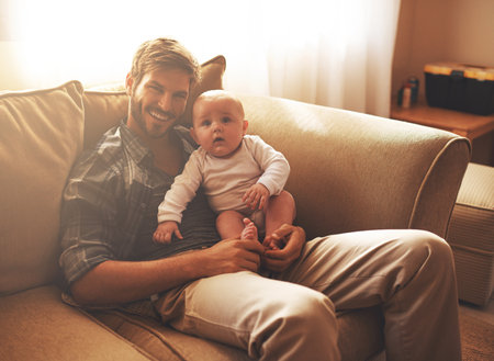 Hes growing up so fast. Cropped portrait of a young father and his baby boy in the living room.の写真素材