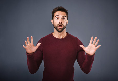 No way That is awesome. Studio shot of a handsome young man looking surprised against a gray...