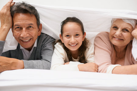 Portrait, grandparents or happy child in bedroom to relax together for bonding in Australia with love or care. Morning, faces or grandmother with fun girl or old man to enjoy quality time on bedの写真素材