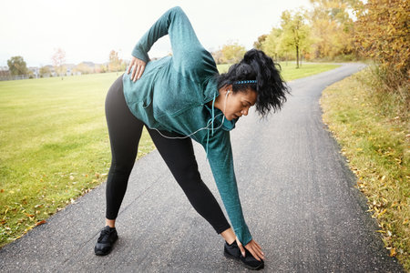 The warmup, just as important as the workout. an attractive young woman stretching while out for a run in nature.の写真素材