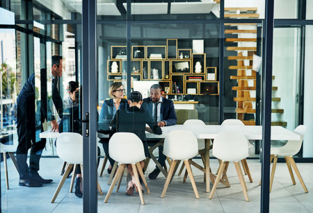 Togetherness is a huge thing for this team. Full length shot of a diverse group of businesspeople having a meeting in a boardroom.の写真素材