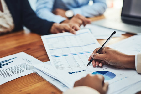Business people, hands and writing on document in meeting for corporate finance, budget or expenses at office. Hand of employee in financial planning, paperwork or marketing for company statisticsの写真素材