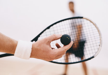 Time to serve up some serious squash skills. a man serving a ball with a racket during a game of squash.の写真素材