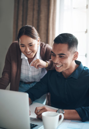 Were in a healthy financial standing. a young couple using a laptop together at home.の写真素材