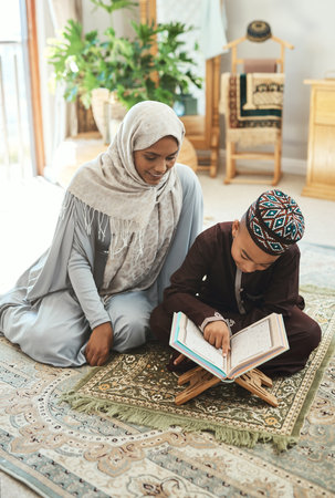Never value expertise over exploration. a young muslim mother and her son reading in the lounge at home.の写真素材