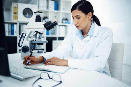 To summarise, its been solved. a young scientist writing notes while conducting medical research in a laboratory.の写真素材
