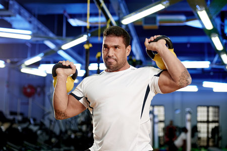 Beast on the bells. a man working out with kettle bells at the gym.