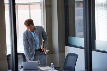 Shutting down for the day. a businessman looking at paperwork in his office.の写真素材