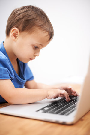 Hell be a typist by age 10. a young boy typing on a laptop.の写真素材
