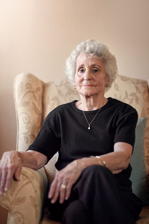 Getting serious in her gray years. Portrait of a senior woman sitting on a chair at home.