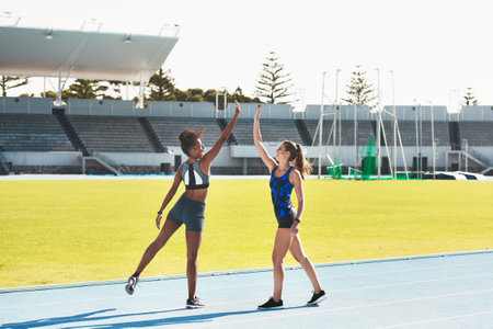 Woman, team and high five on stadium track for running, exercise or training together in athletics outdoors. Women touching hands in celebration for exercising, run or winning in teamwork and fitnessの写真素材