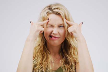 Portrait, funny face and fingers on head with a woman in studio on a gray background looking silly...
