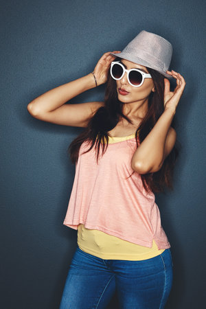 Know youre gorgeous and rock it. Studio shot of an attractive and fun loving young woman posing against a dark background.の写真素材