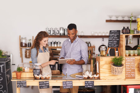 Restaurant owners, tablet and teamwork of people, manage orders and discussion in store. Waiters, black man and happy woman in cafe with technology for inventory, stock check and managing sales.の写真素材