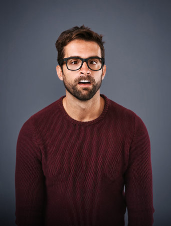 Messing around. Studio shot of a handsome young man pulling funny faces against a gray background.