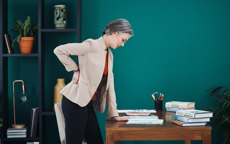 Ouch My back. an attractive mature businesswoman standing and suffering from backache while in her...