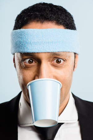 Uh oh, Im a feeling the caffeine. a handsome young man standing alone in the studio and biting a coffee cup.の写真素材