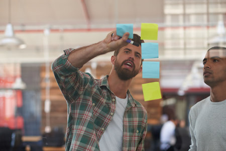 Plans for progress. two colleagues discussing ideas together on sticky notes.の写真素材