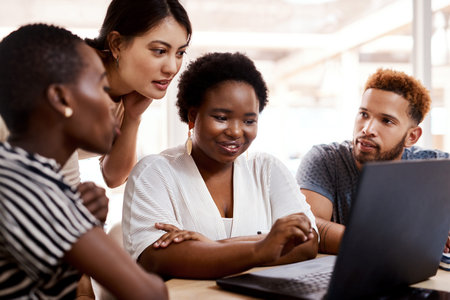 Growing and nurturing creative talent. a group of young creatives working together on a laptop in an...