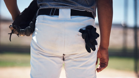 Up close and personal with a baseball player. a man standing on a field and holding a baseball mitt at a match.の写真素材