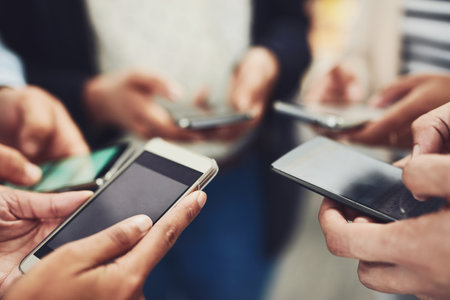 Business people, phone and hands for communication, networking or social media together at office. Hand of group holding mobile smartphone in connection, data sync or sharing information at workplaceの写真素材