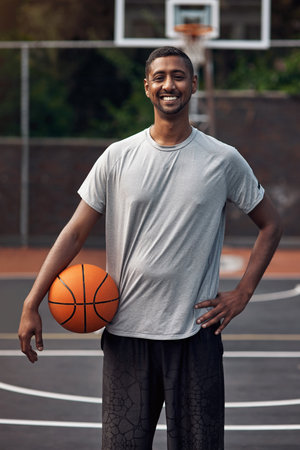 Basketball is my happy escape. Portrait of a sporty young man standing on a basketball court.の写真素材
