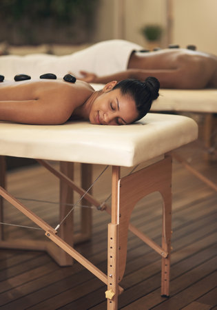 Allow yourself this time to wind down and relax. a young woman getting a hot stone massage at a spa.の写真素材