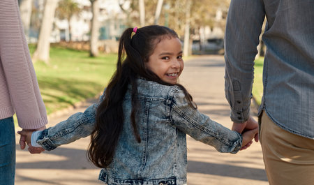 Off to have fun with Dad and Mum. an adorable little girl going for a walk in the park with her parents.の写真素材