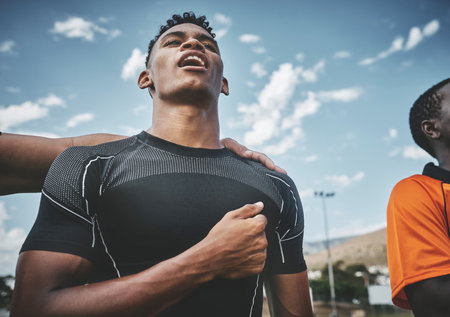 For our team. a team of confident young rugby players standing at attention singing their anthem outside on a field before a rugby match.の写真素材