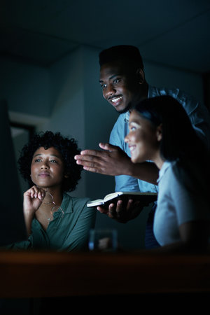 Those who work hard are worthy of success. a group of young businesspeople using a computer together during a late night at work.の写真素材