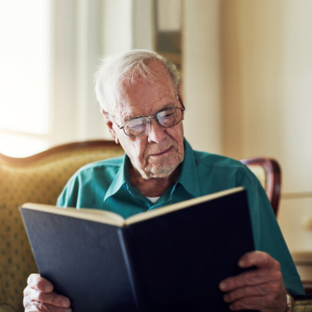Hes never lost interest in reading. a senior man reading a book while relaxing at home.の写真素材
