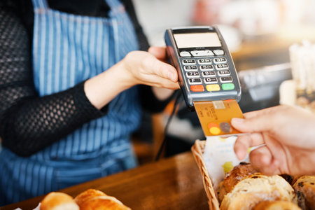 Credit card payment, bakery and hands with a machine at a restaurant for a service or food. Cafe, pay and a customer paying or buying a product at a coffee shop with a transaction from a workerの写真素材