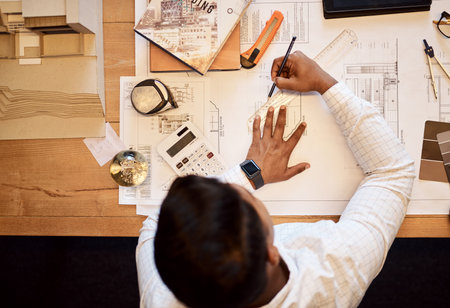 The highest quality designs are created with the highest accuracy. High angle shot of an architect using a ruler to draw a building plan.の写真素材