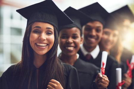 The rest of their life is ahead of them. a group of fellow students standing in a row on graduation day.の写真素材