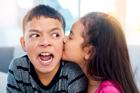 Okay enough with the kisses now. an adorable little girl kissing her big brother on the cheek at home.の写真素材