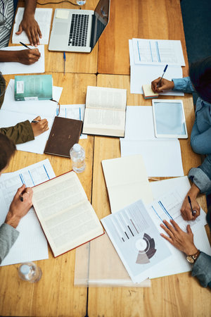 Theyve got all their study material ready and available. High angle shot of a group of unrecognizable university students studying in the library.の写真素材