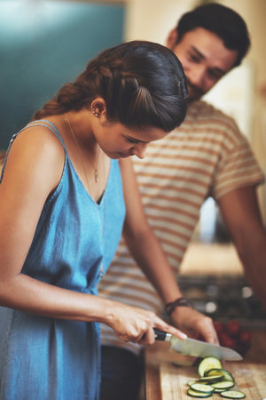 Shes starting dinner early. an affectionate young couple cooking together in their kitchen at home.の写真素材