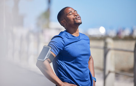 Fitness, training and tired man runner outdoors for break from exercise, cardio or running on blurred background. Workout, stop and breathe by athletic male outside for marathon, run or sport routineの写真素材