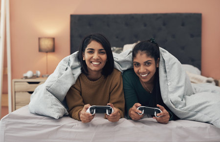 Im winning this round. two young women playing video games at home.